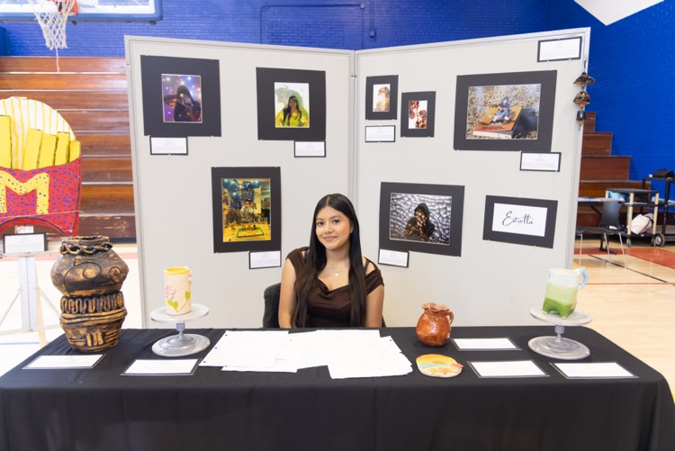 student posing with their artwork