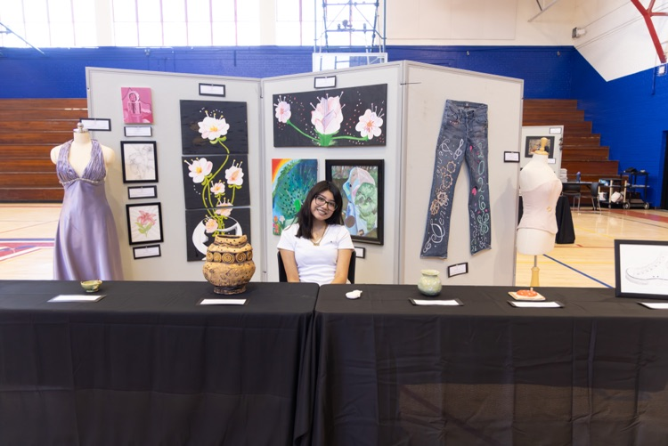 student posing with their artwork