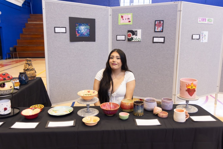 student posing with their artwork