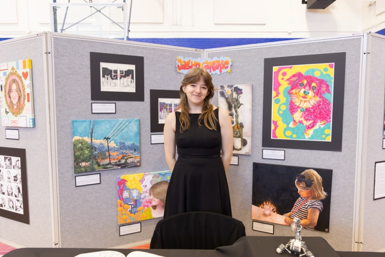 student posing with their artwork