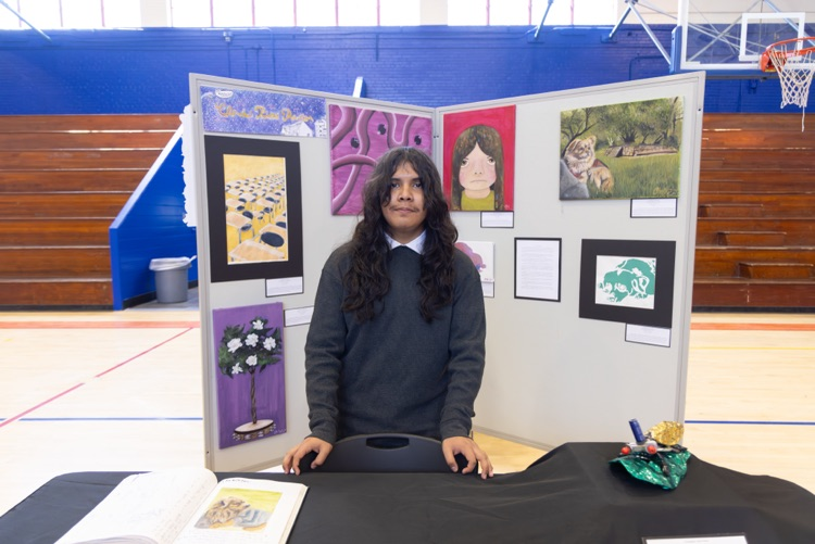 student posing with their artwork