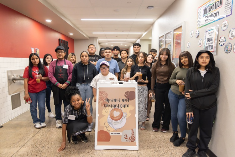 Large group of students pose behind sign