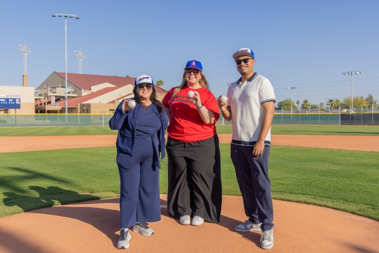 three people pose on baseball mound with baseballs