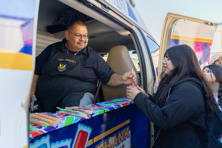 A man hands a student a candy bar at a school food truck.