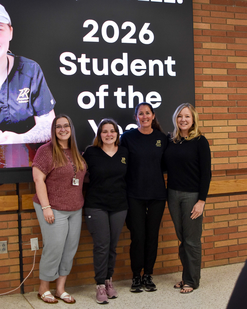 A group stands in front of a screen.