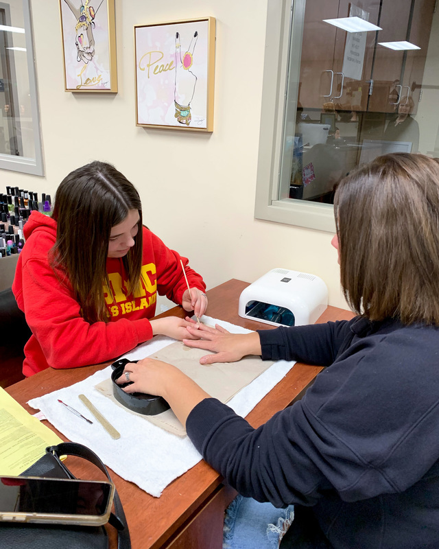 Kaitlyn works on a client's nails.