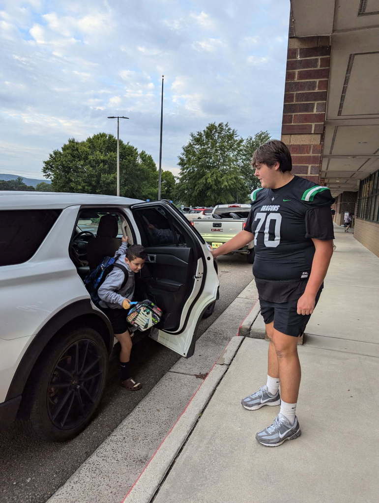 Dragons football players helping a morning car riders.