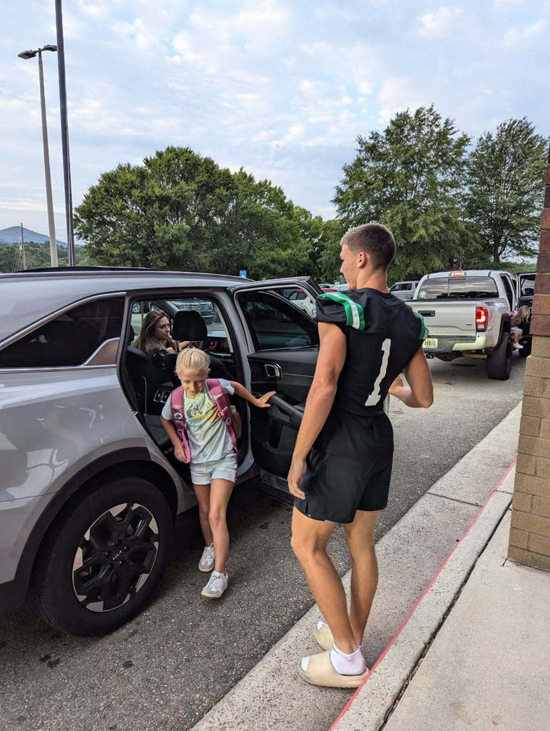 Dragons football players helping a morning car riders.