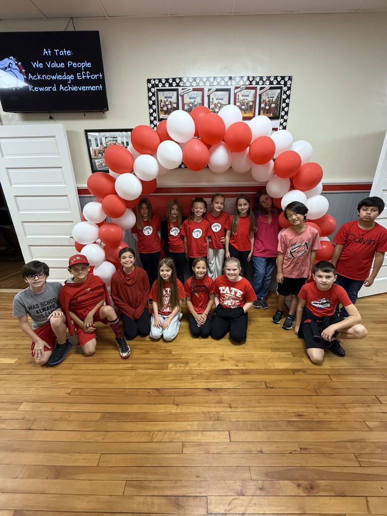 Group of fourth grade students kneeling in front of a balloon arch  wearing red for red ribbon week
