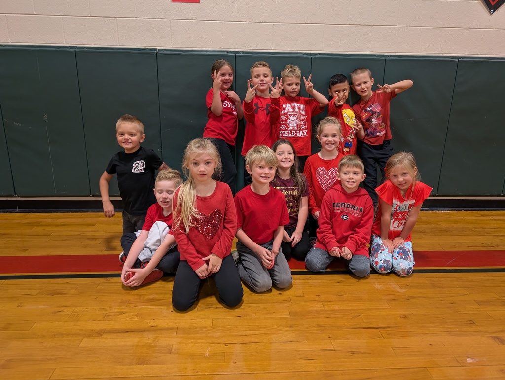 Group of first grade students kneeling in gym, wearing red for red ribbon week