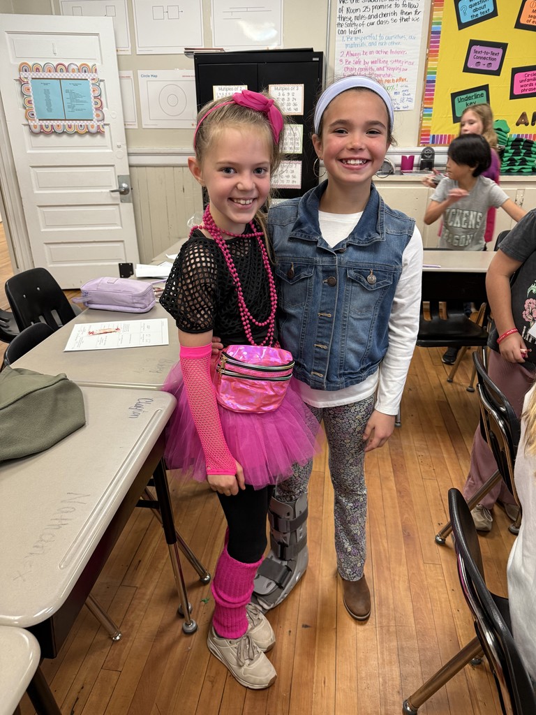 Two  fourth grade students standing in front of the classroom in decade clothes for red ribbon week