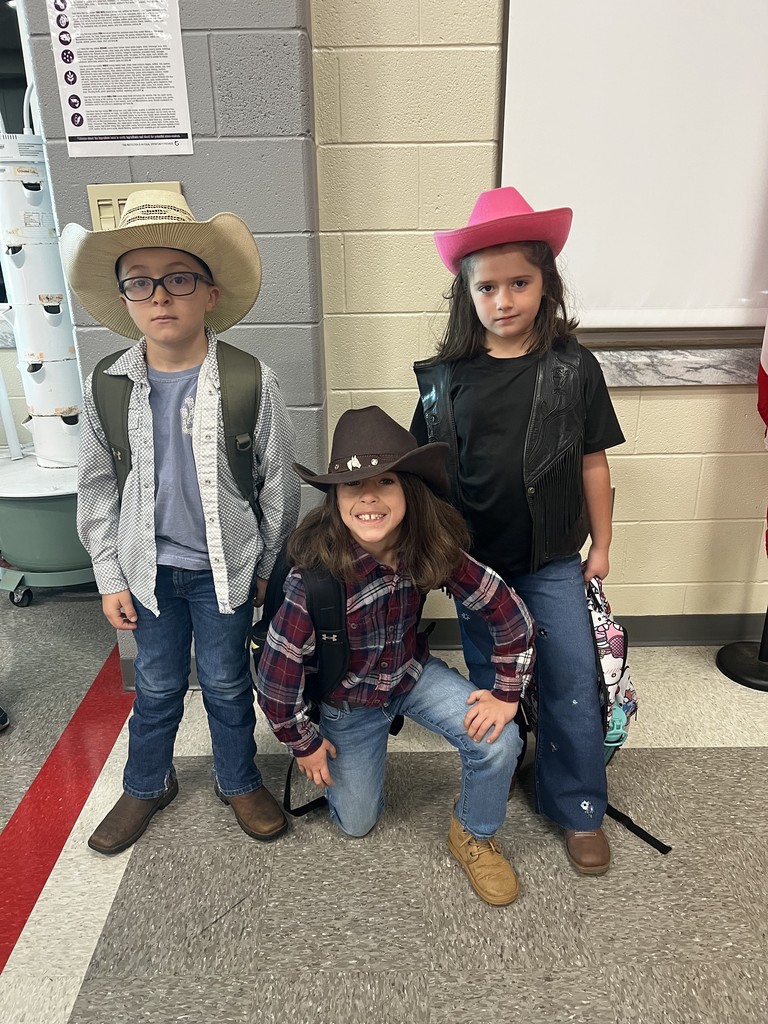 Three students, two standing, one kneeling, in the cafeteria dressed as cowboys to celebrate red ribbon week