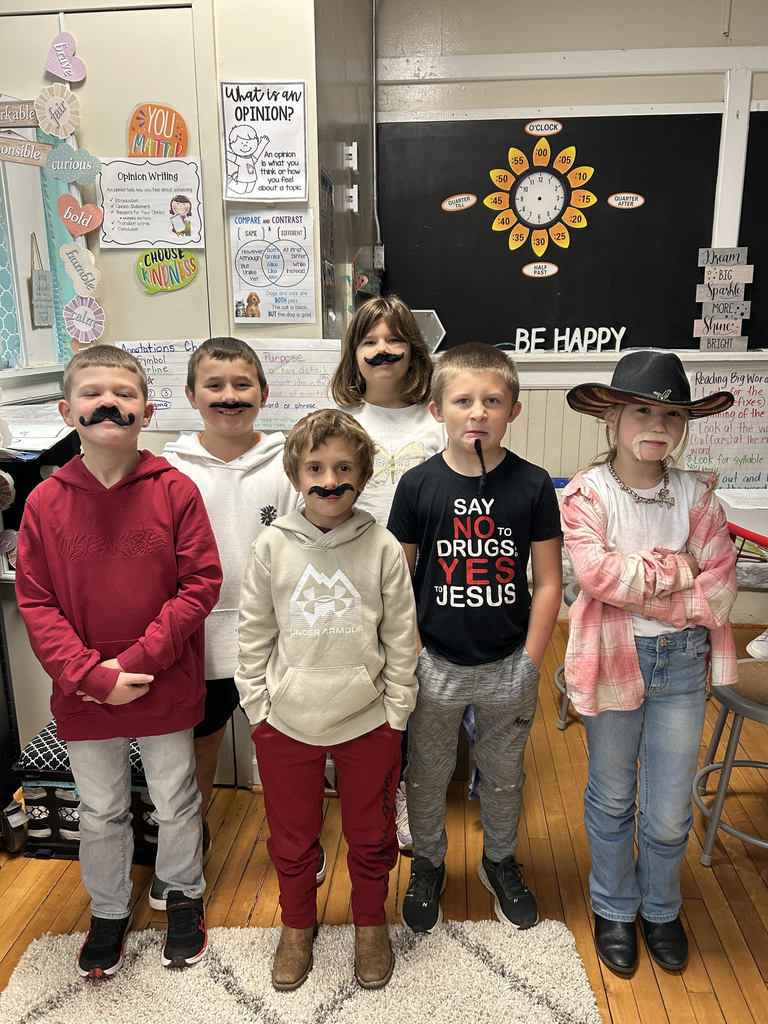 Group of students standing in front of the classroom wearing fake mustaches for red ribbon week