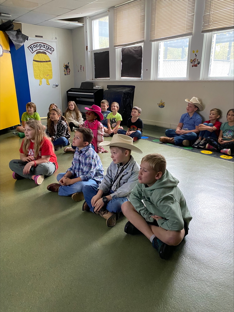 Group of kids sitting in the floor who appear to be listening quitely