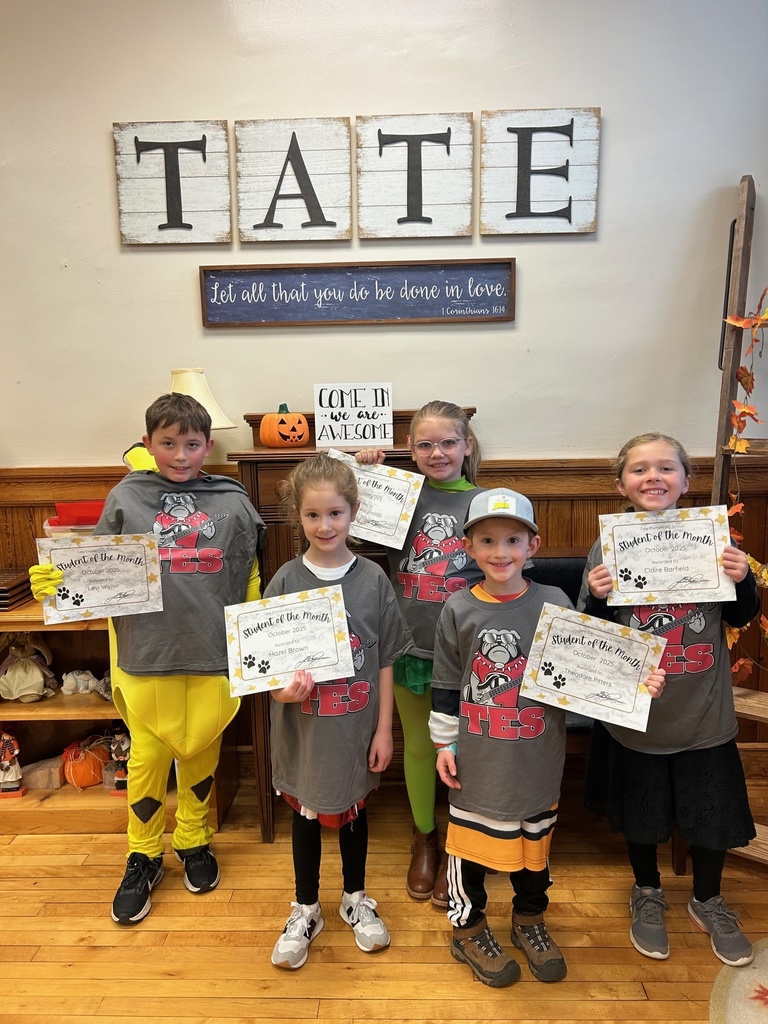 Group of students wearing the same shirt in the front office holding up student of the month awards