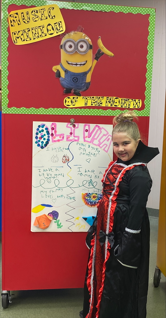 Female student dressed as a vampire in front of a student made poster with a minion bulletin board in the background