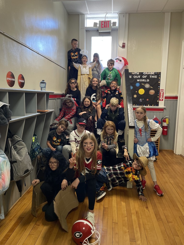 Group of kids sitting on steps of the school dressed in halloween costumes 