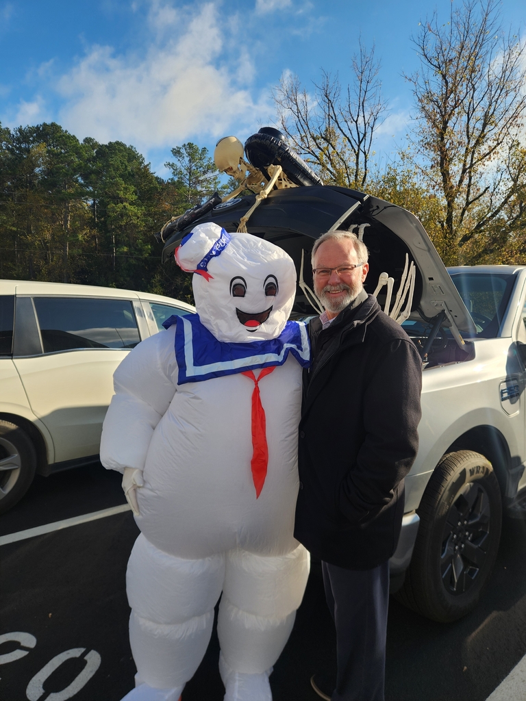 Man and michelin man standing outside in front of a car