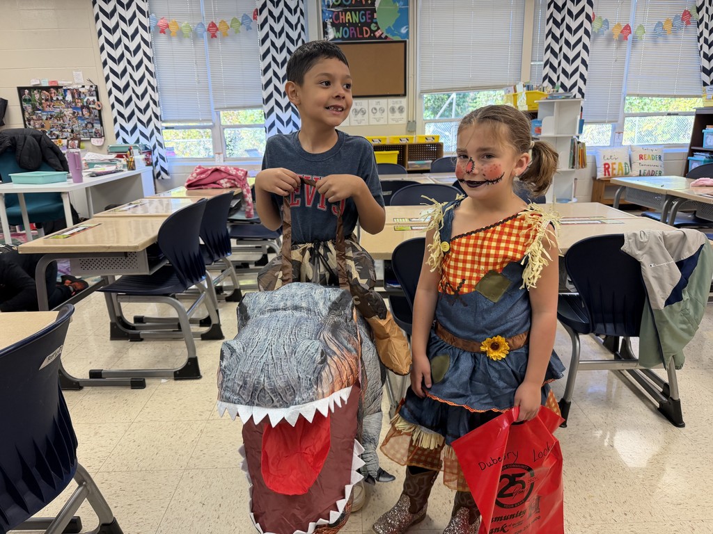 Two kids in their classroom dressed in halloween costumes 