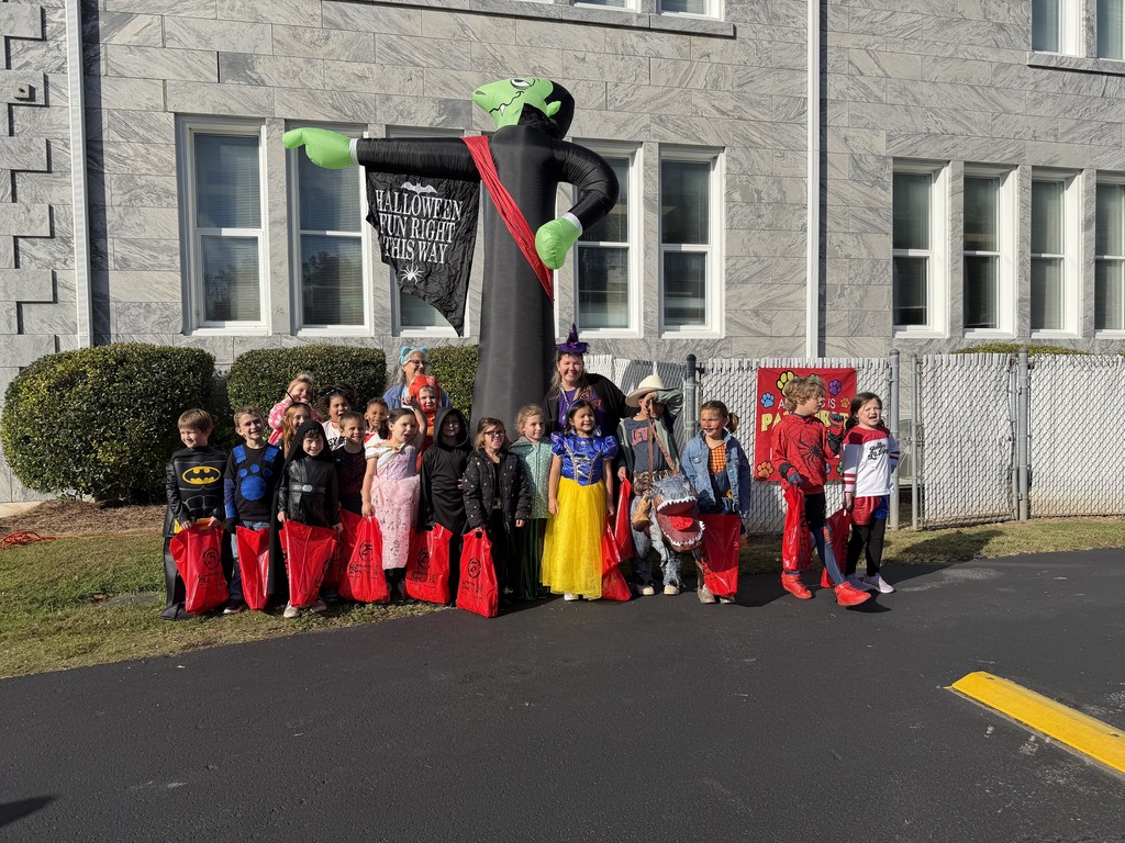 Group of kids standing in front of the school dressed in halloween costumes 