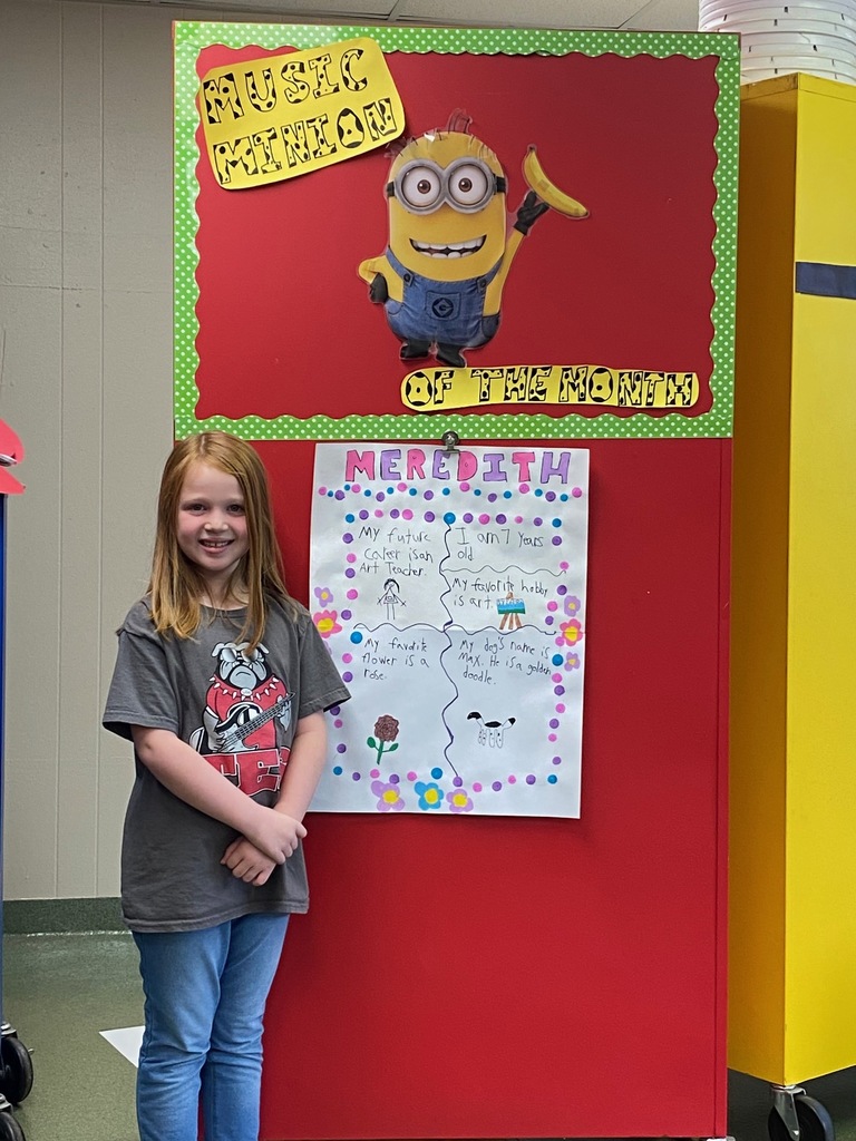 Female student in front of a decorated door with a minion and a homemade poster. 