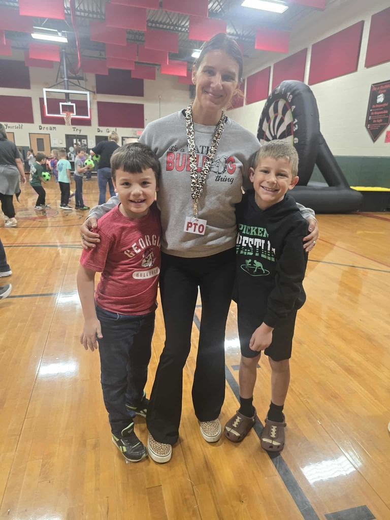 Adult woman side hugging two students in the gym