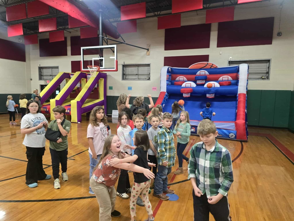 Group of  kids standing in a school gym waiting for their turn to shoot basketballs at an inflatable goal