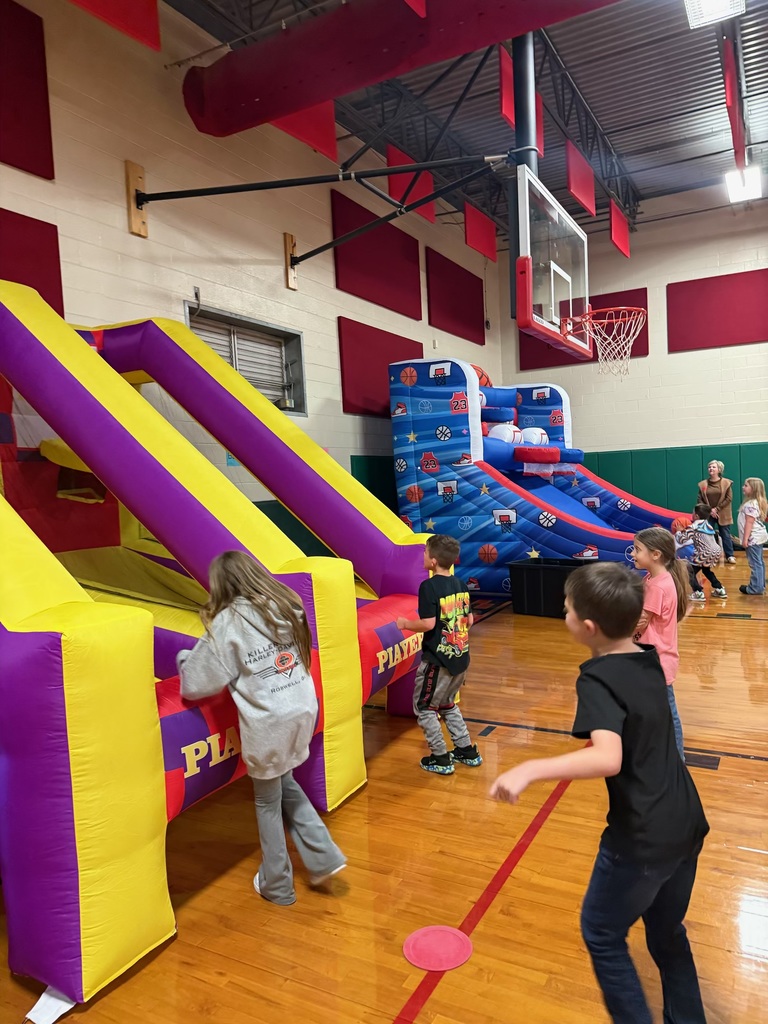 Group of kids in a school gym playing an inflatable game