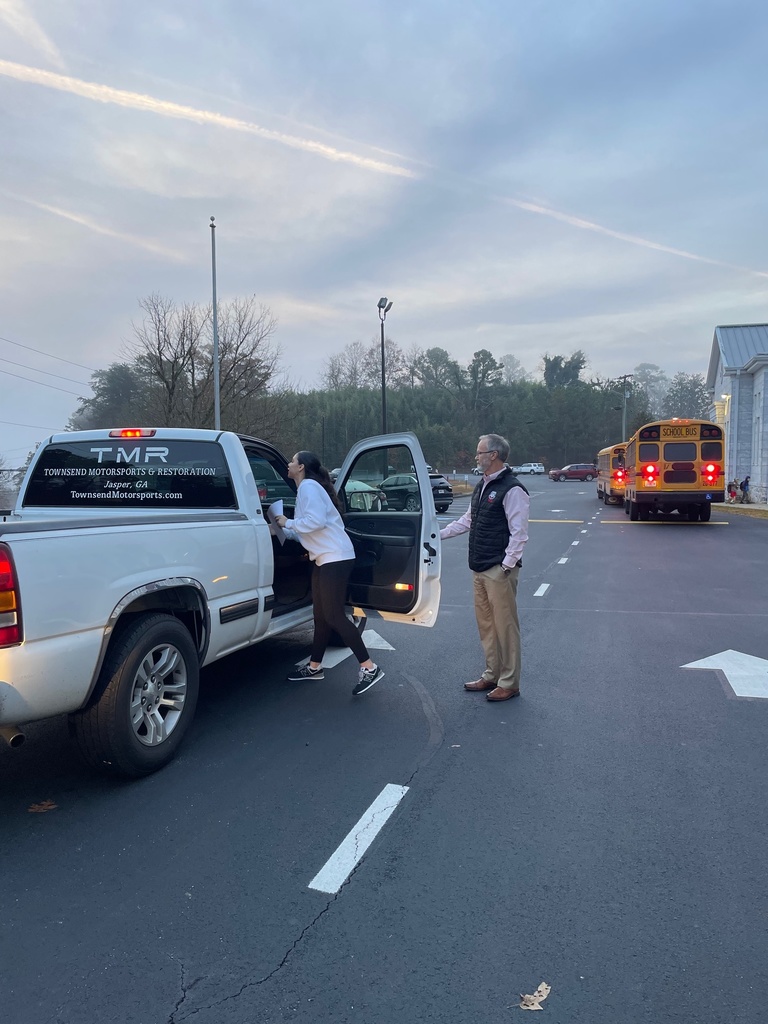 Man and high school student standing beside a white truck with the passenger door open 