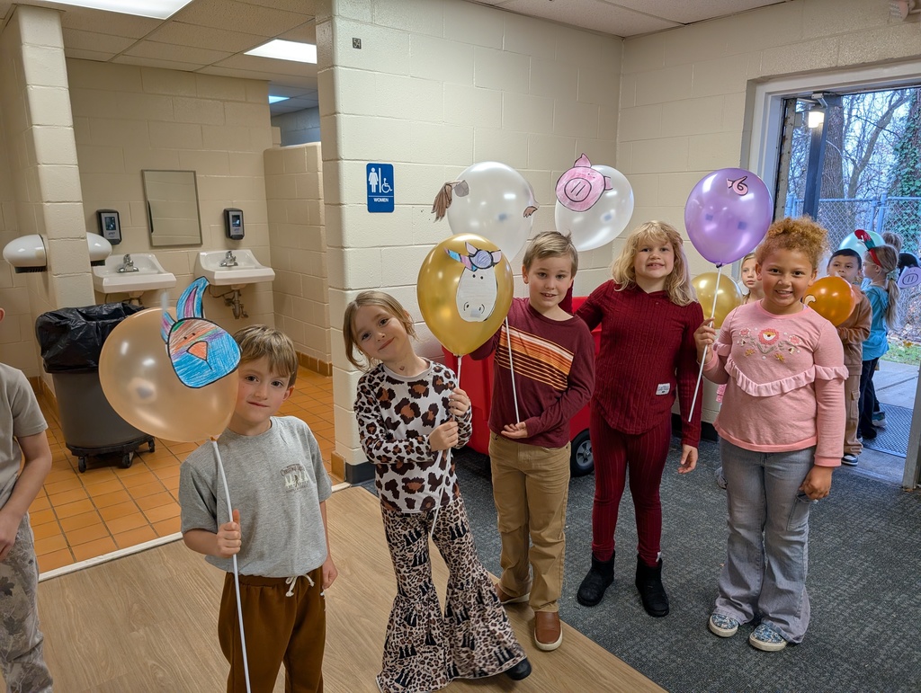 Group of kids in school hallway holding balloons on sticks 