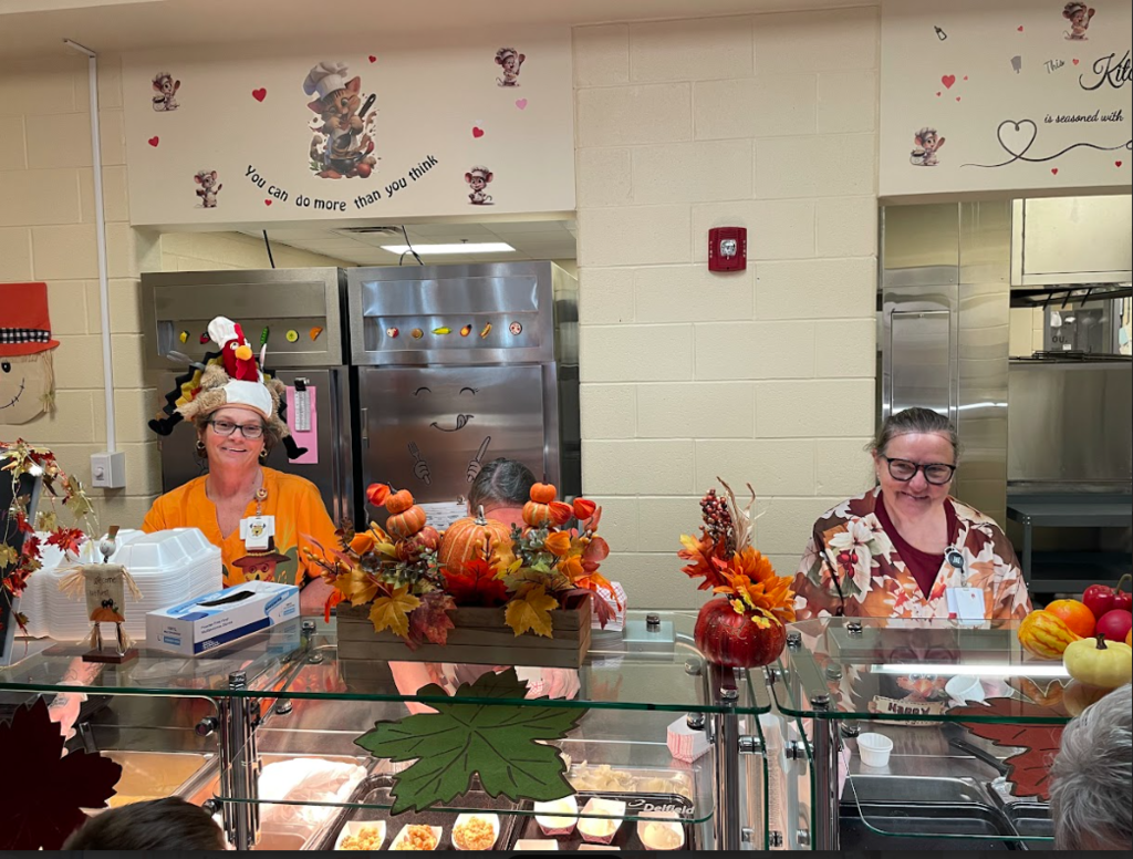 Cafe workers standing behind food counter serving food dresses in fall clothes with fall decorations