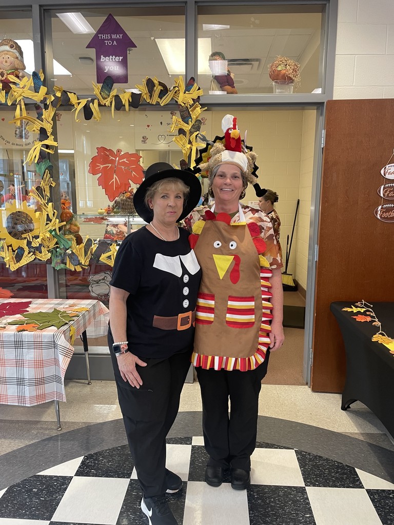 two  women standing closely side by side dressed as pilgrim and turkey
