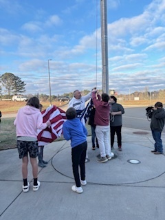 Students attaching the flag to the flagpole