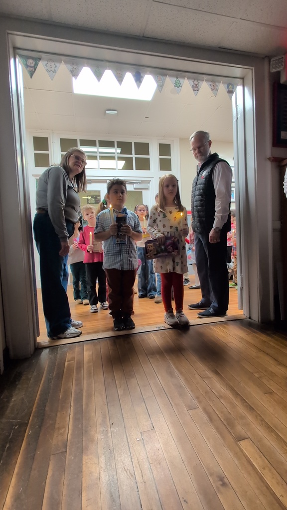 Two adults, two children standing in double doorway. children are holding a candle and a toy