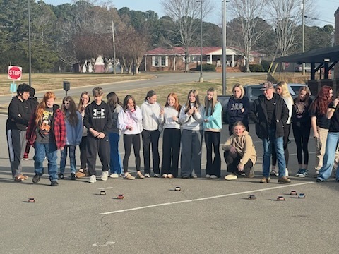 Students and teachers watching the solar cars in the parking lot