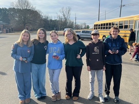 Six students standing in a row holding their solar cars