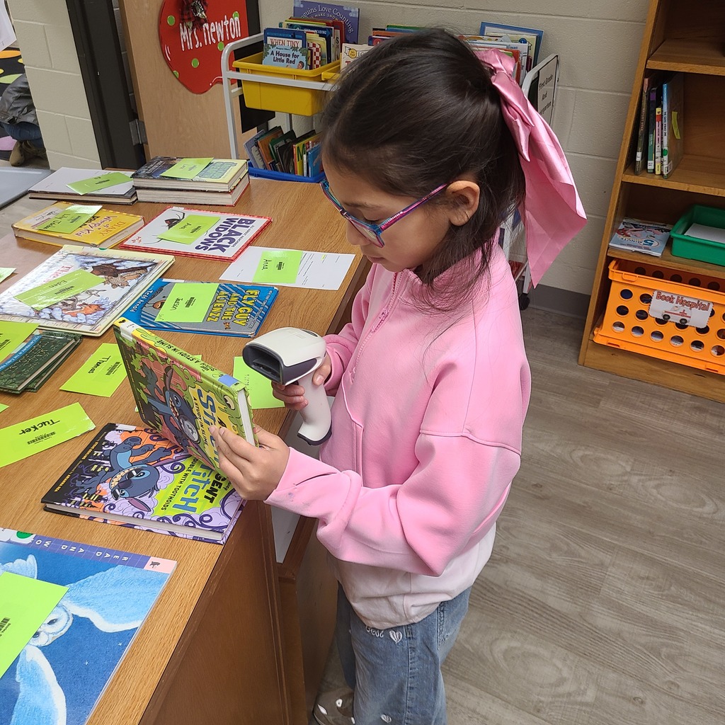 A child wearing a pink shirt and a pink bow scanning books