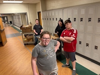 Students in hallway with cart full of packages