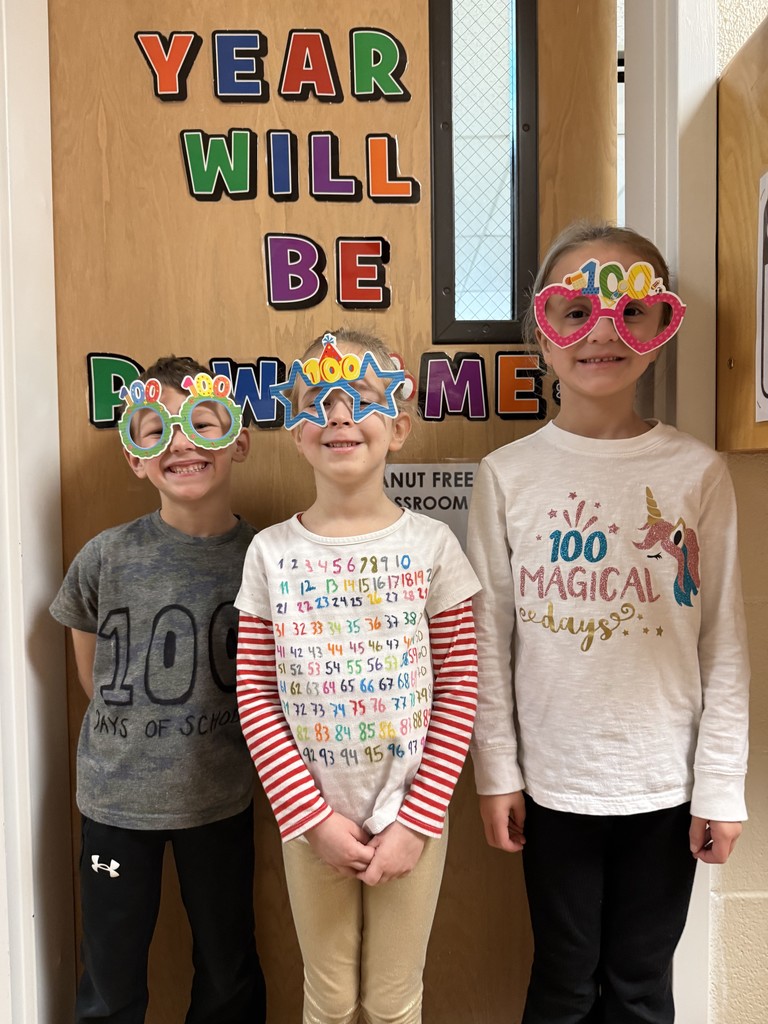 Three students standing in front of a door wearing glasses with the number 100 on it