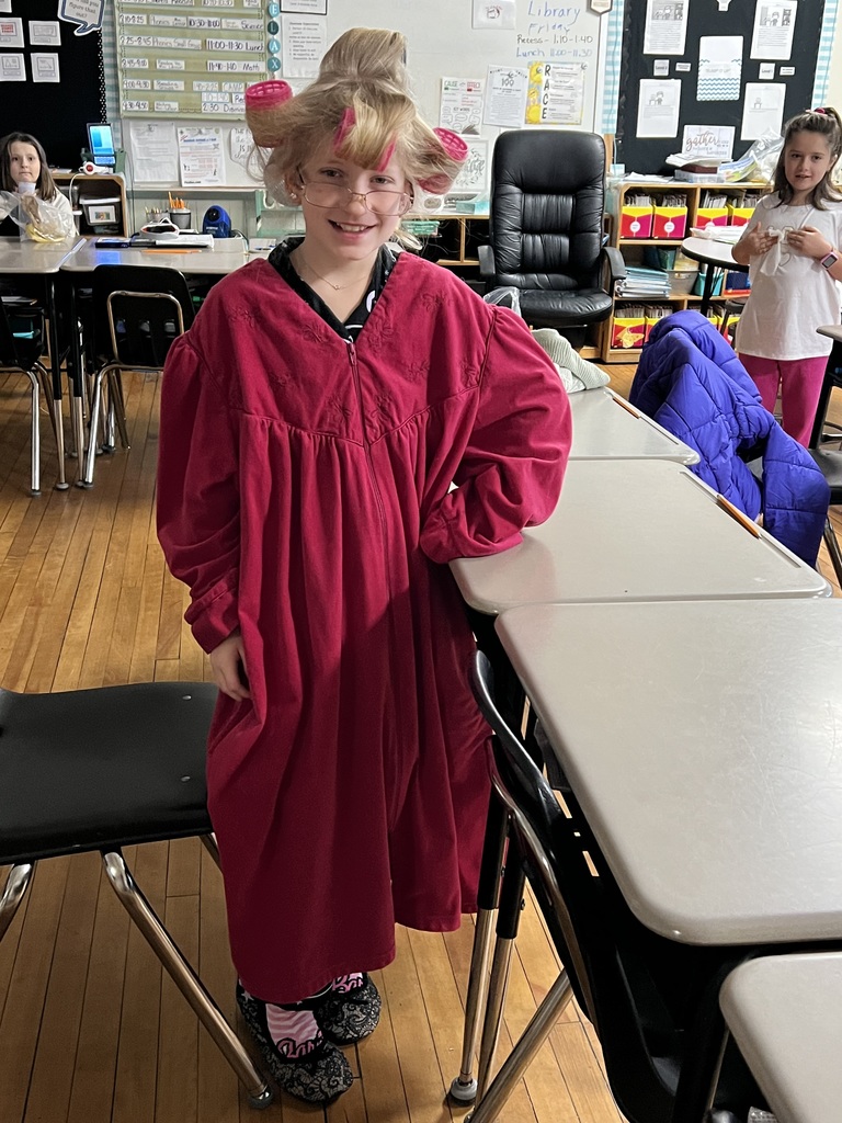 Female student standing in a classroom with rollers in her hair wearing a robe