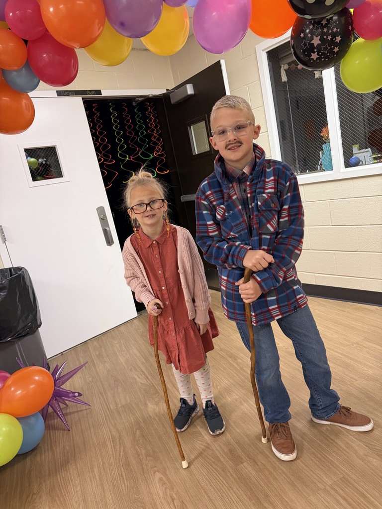 Two kids dressed as elderly people surrounded with balloons
