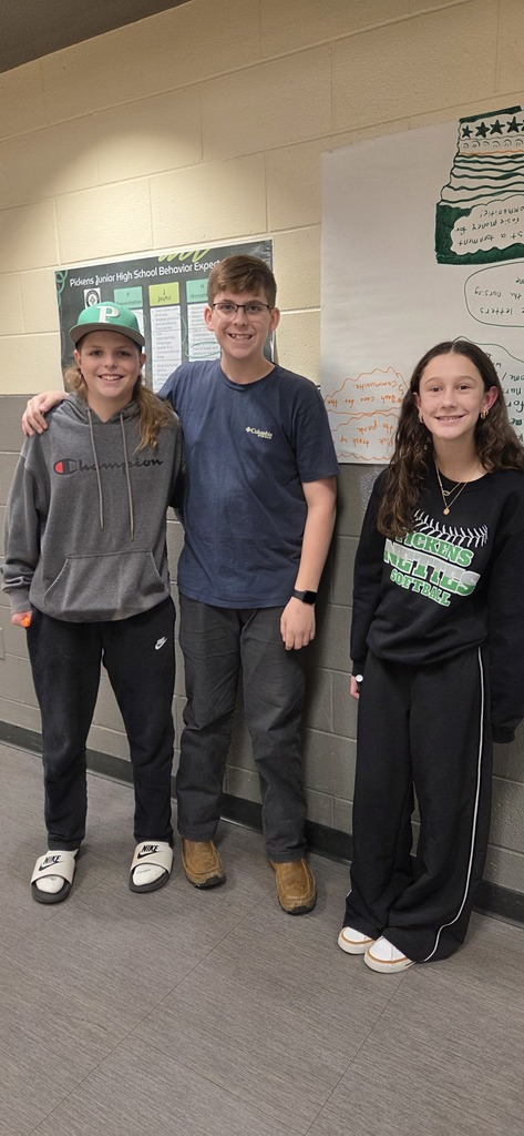 3 students standing, facing camera and smiling