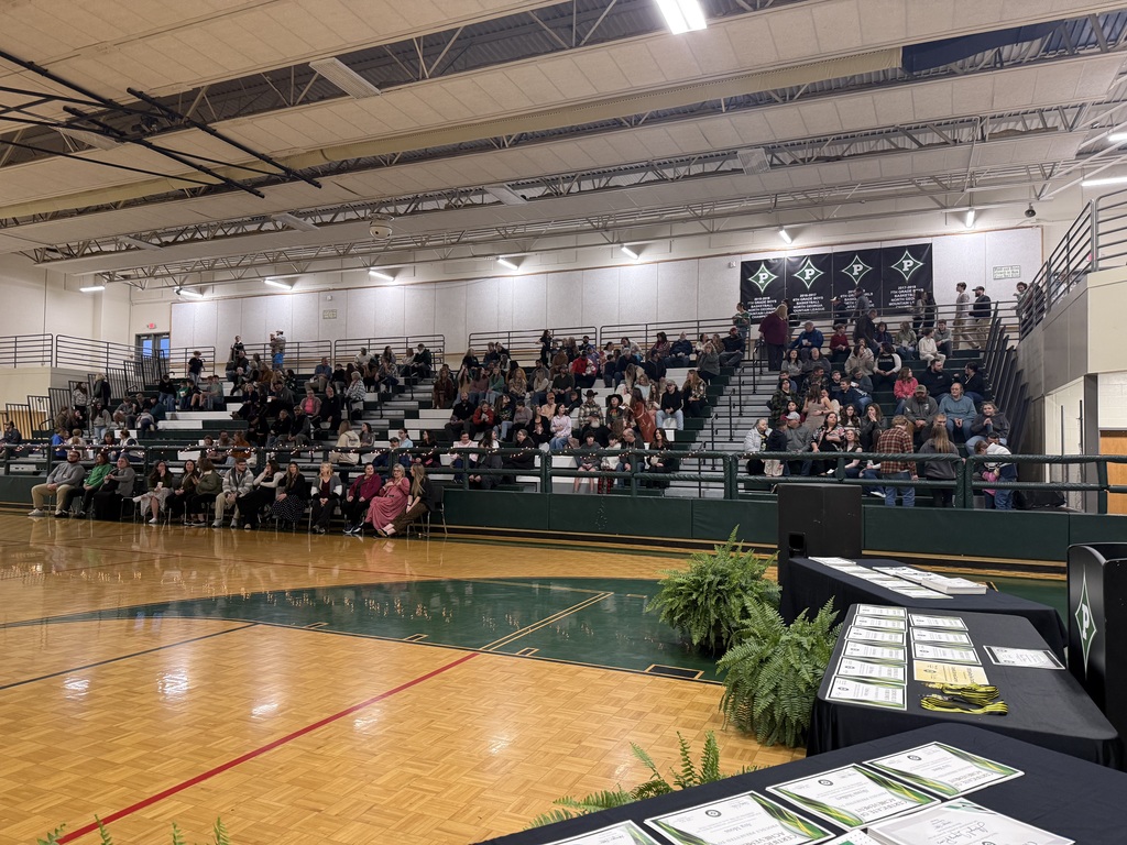 Attendees gathering in the bleachers and certificates laid out ready for presentation