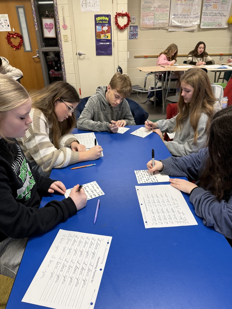 Students sitting at a table and practicing handwriting