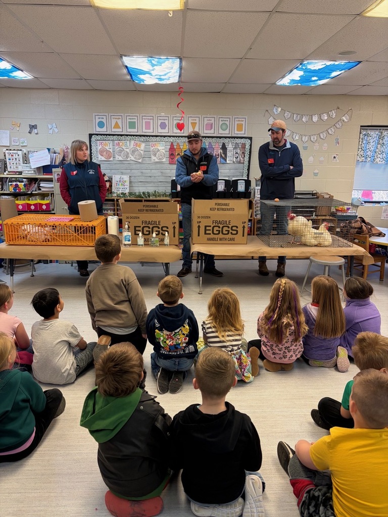 Three adults presenting baby chicks and chickens to a classroom 