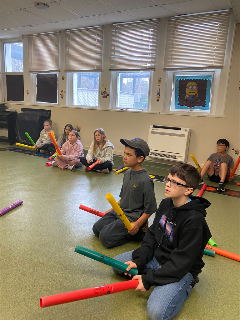 A group of kids sitting on the floor with musical instruments called boonwackers.