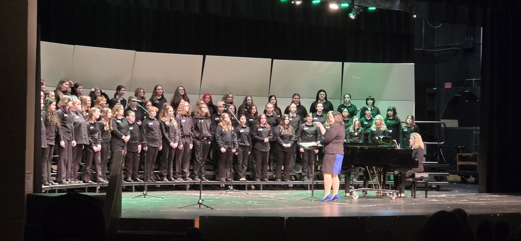 Chorus students standing on risers with teacher directing