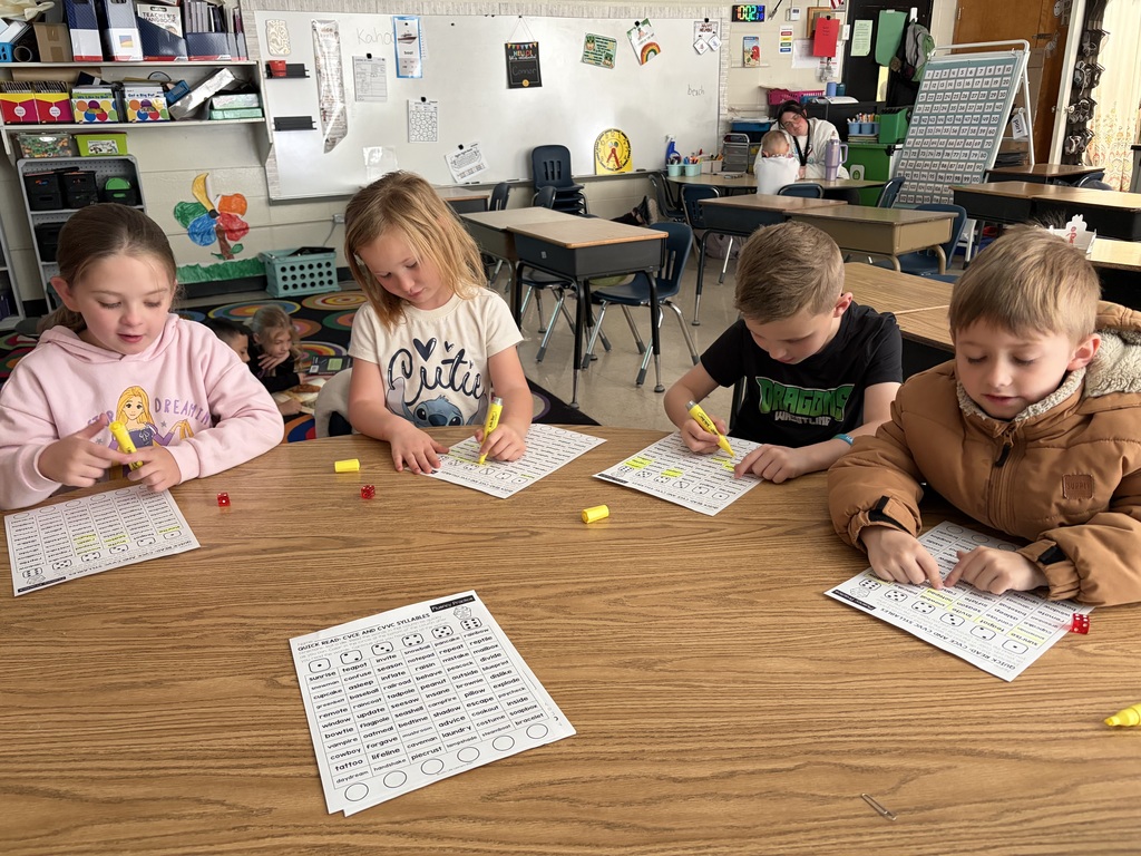 Kids sitting at a table looing at papers with highlighters in theor hands