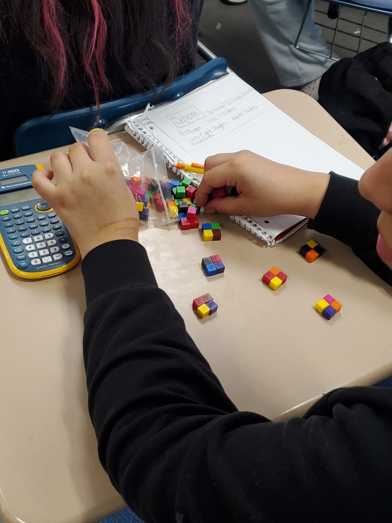 Student working with calculator, notebook and colorful cubes