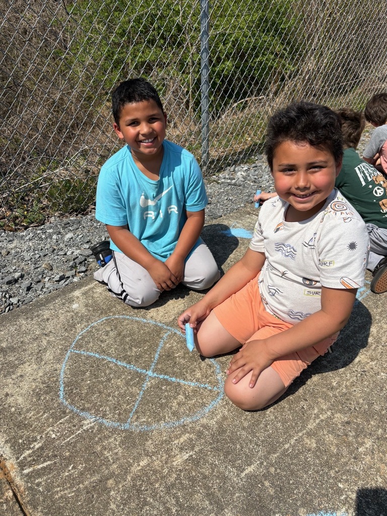 two male students sitting on the sidewalk with sidewalk chalk